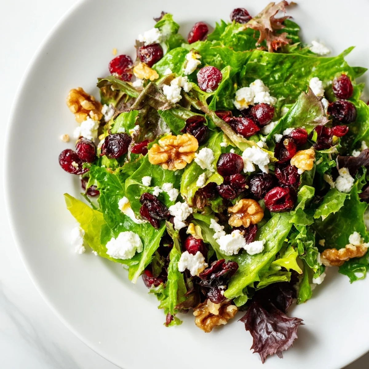 A close-up view of Seasonal Cranberry and Walnut Celebration Salad showing glossy walnuts and vibrant cranberries on a bed of greens, ready for a dinner party.