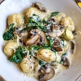 One-pan creamy mushroom and spinach gnocchi, garnished with cracked pepper and extra cheese.