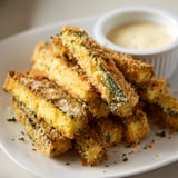 A close-up view shows the crunchy panko and Parmesan coating on these baked Crispy Parmesan Zucchini Fries with Dipping Sauce.