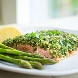 Fresh parsley and dill create a vibrant green crust on the baked salmon, paired with glistening roasted asparagus and lemon wedges.