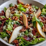 A vibrant salad of frisée, ripe pears, blue cheese, and prosciutto, beautifully plated for a light lunch.