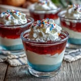 Bright, festive 4th of July Firecracker Jello Shots adorned with whipped cream and sprinkles.