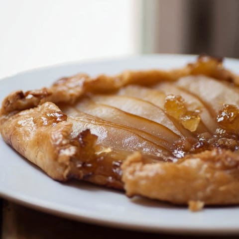 A whole Rustic Pear and Ginger Galette with a beautifully browned crust, ready to be sliced and served warm with a scoop of vanilla ice cream.