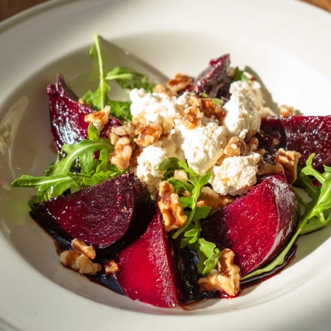 Close-up of roasted beet goat cheese salad with walnuts and balsamic dressing drizzle.