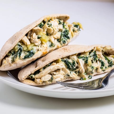 Golden-brown, crispy spinach artichoke chicken stuffed pita pockets fresh from the oven, with melted cheese and herbs.