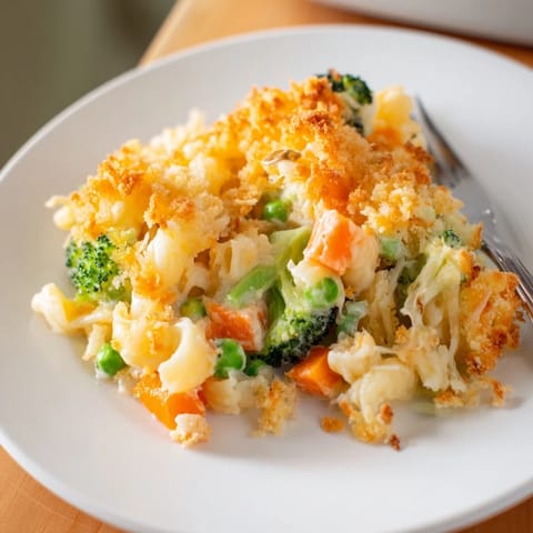 A serving of Garden Veg Mac and Cheese with golden baked cheese and visible peas, broccoli, and carrots.