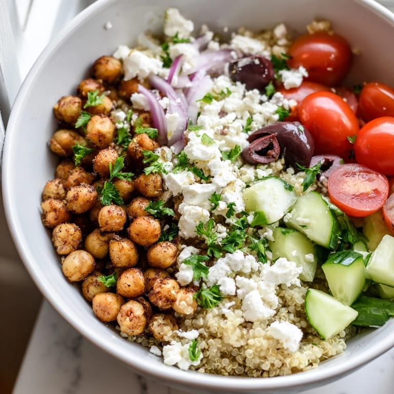 Fluffy quinoa, crispy roasted chickpeas, and tangy feta top a vibrant Mediterranean grain bowl with fresh veggies.