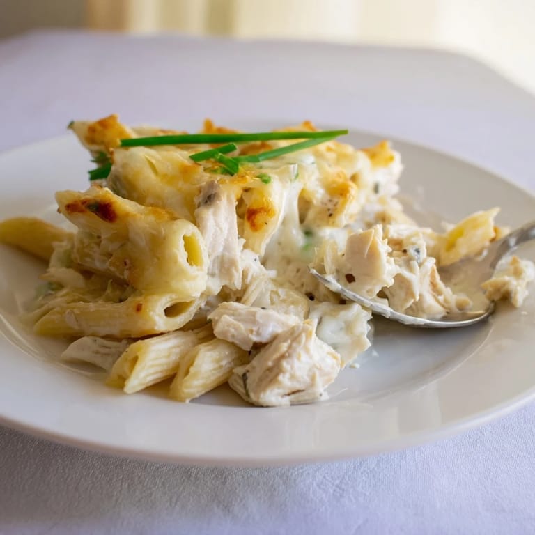 Family-style Chicken Ranch Pasta Bake casserole with golden cheese crust, served with a green salad on the side.