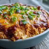 Golden, bubbly Buffalo Chicken Dip fresh from the oven, topped with melted cheddar and fresh green onions.