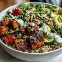 Colorful Customizable Grain Bowl with roasted sweet potato, avocado, and tahini drizzle, ready to enjoy.