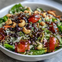 A vibrant Rainbow Salad Bowl with quinoa, chickpeas, and colorful vegetables topped with crunchy nuts and a zesty lemon dressing.